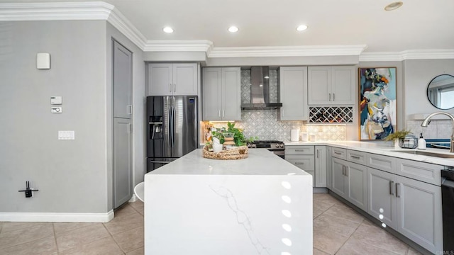 kitchen with stainless steel appliances, a sink, a kitchen island, gray cabinets, and wall chimney exhaust hood