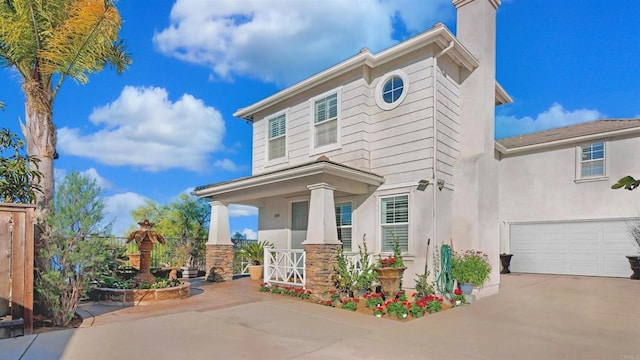 view of front facade with a chimney, stucco siding, a porch, concrete driveway, and a garage