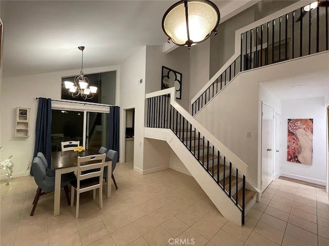 tiled dining area featuring baseboards, a high ceiling, an inviting chandelier, and stairs