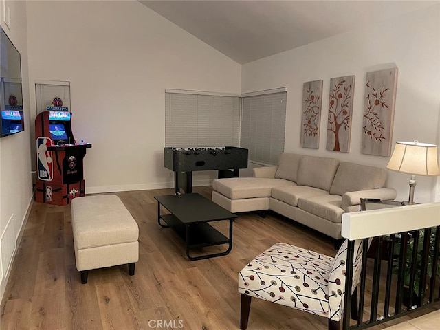 living area with high vaulted ceiling, baseboards, and wood finished floors