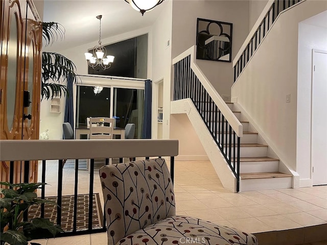 stairway with tile patterned floors, baseboards, a notable chandelier, and a high ceiling