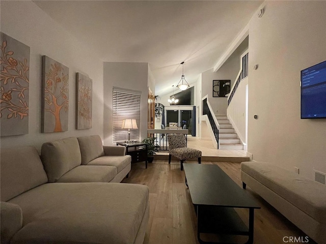 living area with a chandelier, stairway, lofted ceiling, and wood finished floors