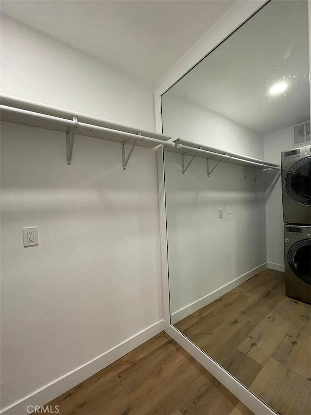 spacious closet featuring wood finished floors and stacked washer / dryer