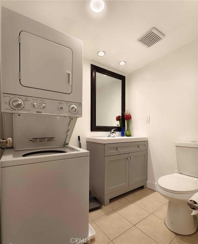 laundry area featuring visible vents, stacked washer and dryer, recessed lighting, light tile patterned flooring, and laundry area