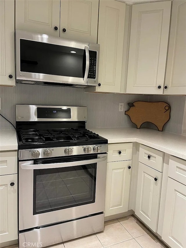 kitchen with light tile patterned floors, appliances with stainless steel finishes, white cabinets, and light countertops