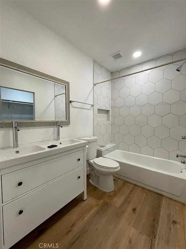 full bathroom featuring visible vents, toilet, wood finished floors, and a sink