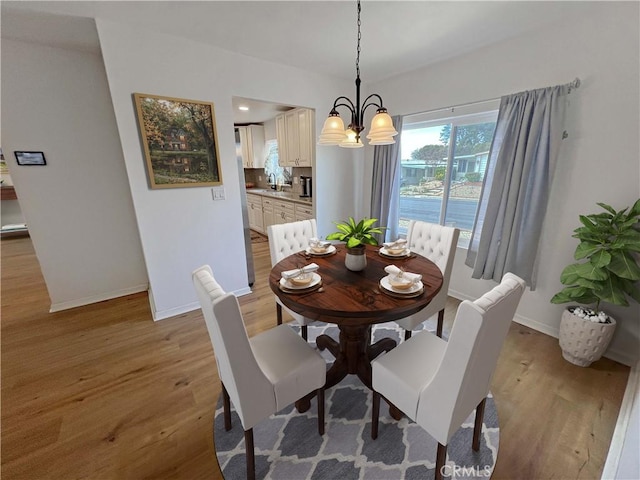 dining room featuring light wood finished floors, a notable chandelier, and baseboards