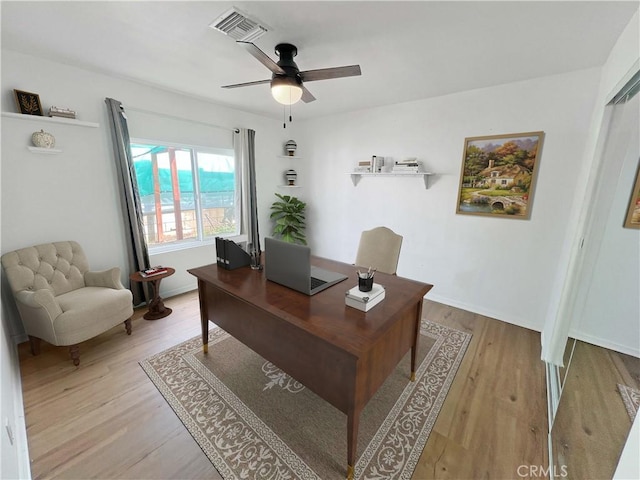 office area with visible vents, baseboards, light wood-style floors, and a ceiling fan