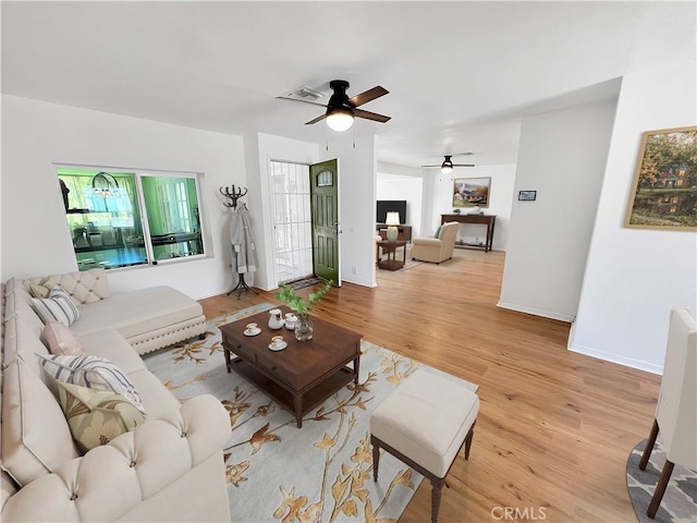 living room featuring light wood-type flooring, baseboards, and visible vents