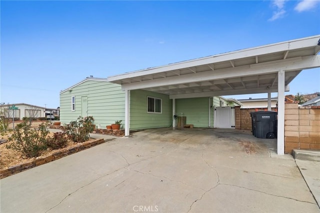 exterior space with a carport, driveway, and fence