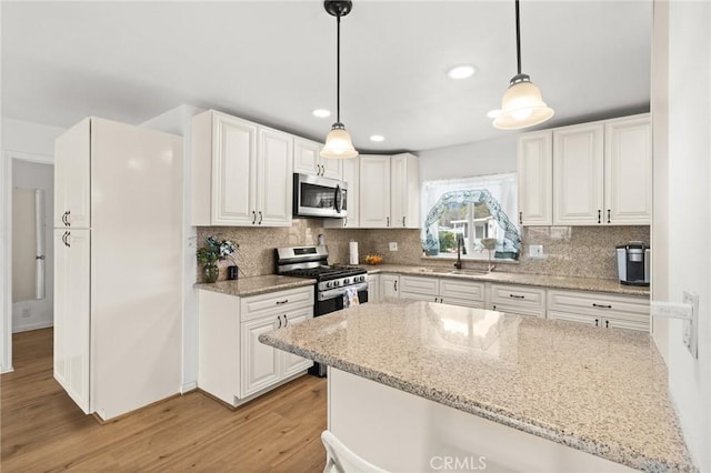 kitchen with white cabinets, light wood finished floors, appliances with stainless steel finishes, and a sink