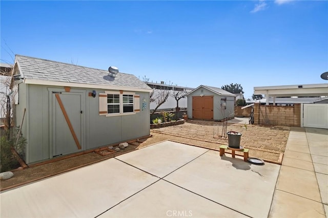 view of patio featuring a storage unit, an outdoor structure, and fence