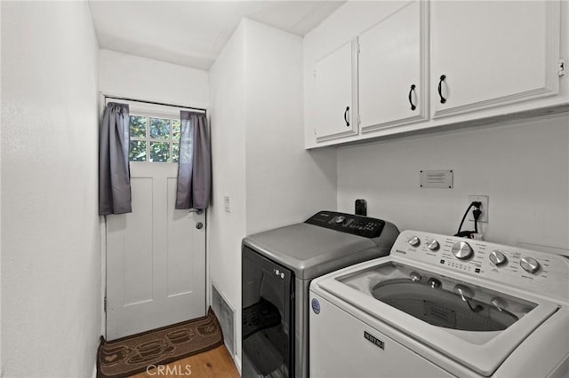 washroom with cabinet space, independent washer and dryer, and wood finished floors