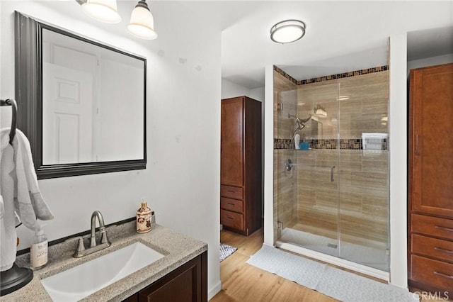 full bathroom featuring a stall shower, vanity, and wood finished floors