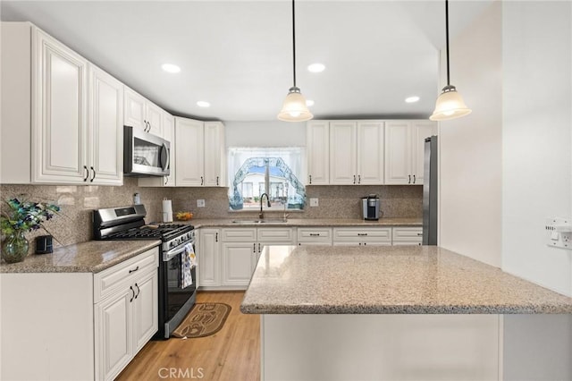 kitchen with light wood-style flooring, white cabinetry, stainless steel appliances, and a sink