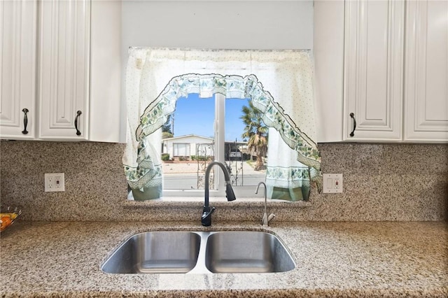 kitchen featuring a sink, backsplash, and white cabinetry