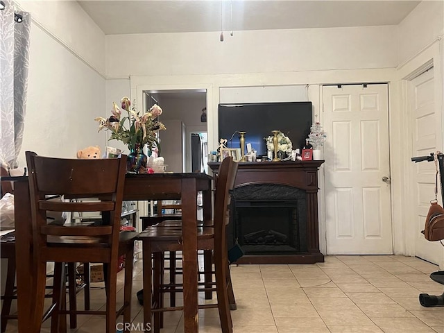 dining area with a high end fireplace and light tile patterned floors