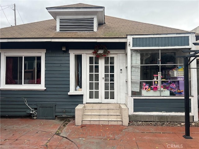 entrance to property with french doors and roof with shingles