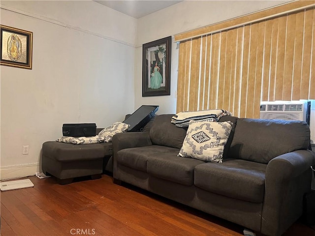 living room with cooling unit, baseboards, and wood finished floors