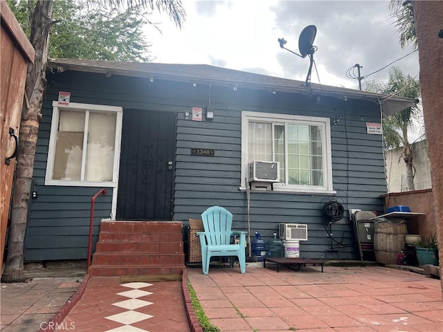 back of house with entry steps, a patio area, and a wall mounted AC