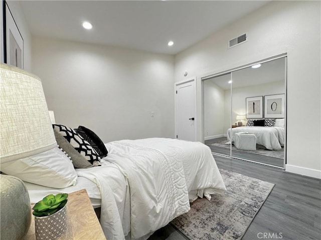 bedroom with baseboards, visible vents, wood finished floors, a closet, and recessed lighting