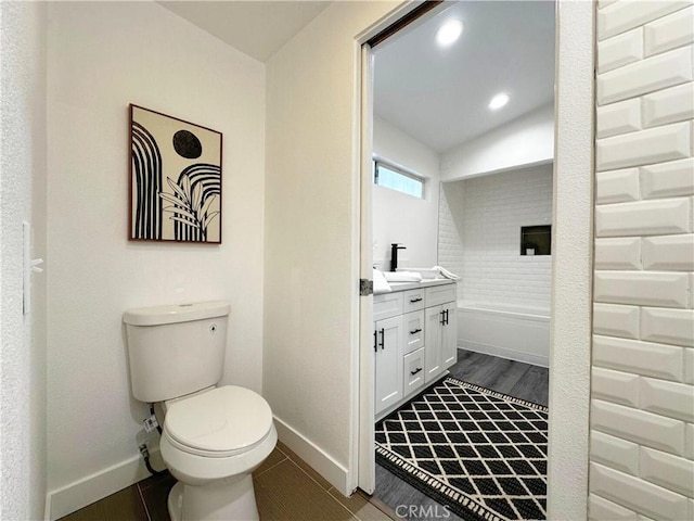 bathroom with toilet, recessed lighting, wood finished floors, vanity, and baseboards