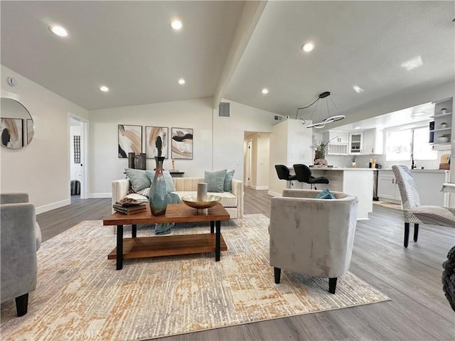 living area with lofted ceiling with beams, light wood-style flooring, visible vents, and baseboards