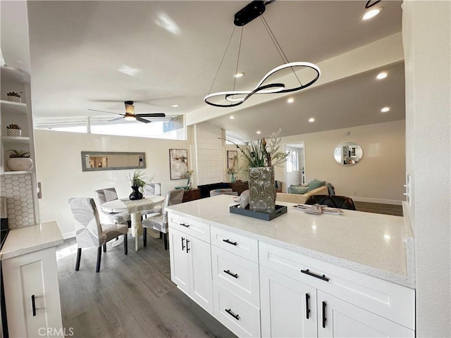 kitchen featuring lofted ceiling, dark wood-style floors, open floor plan, light stone countertops, and white cabinetry