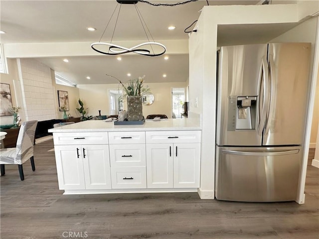 kitchen with lofted ceiling, white cabinets, stainless steel fridge, and wood finished floors