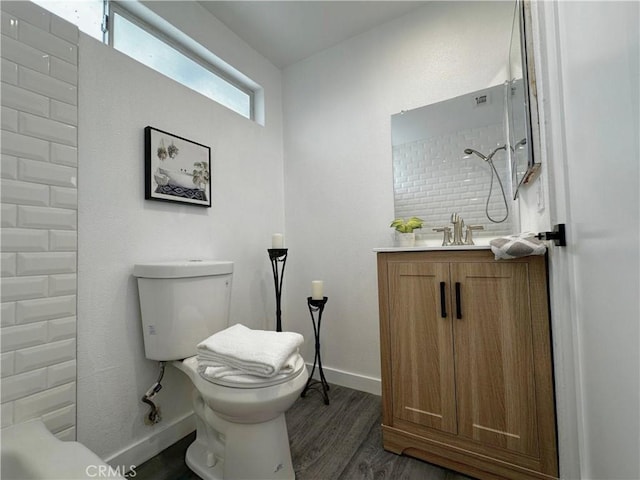 bathroom with a shower, toilet, vanity, wood finished floors, and baseboards