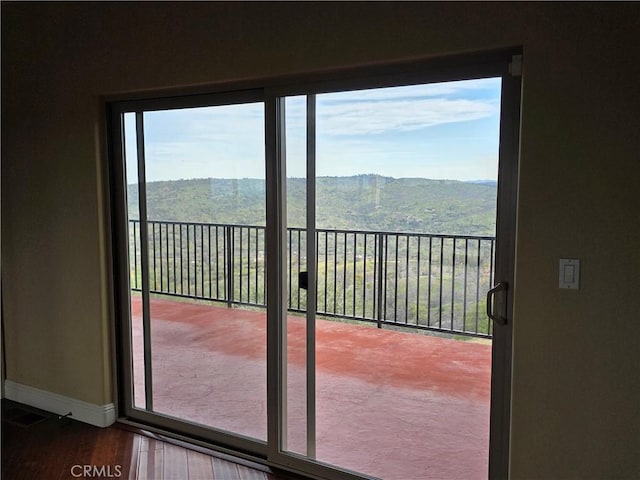 doorway with a wealth of natural light, a mountain view, baseboards, and wood finished floors