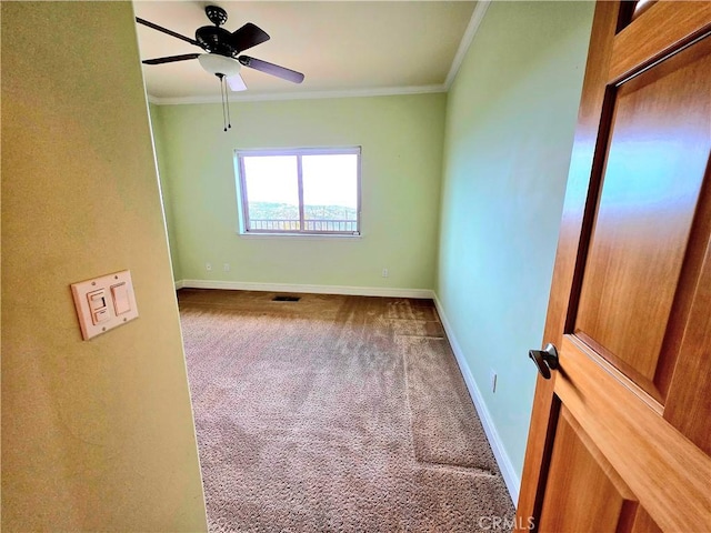 unfurnished room featuring carpet floors, a ceiling fan, baseboards, visible vents, and crown molding