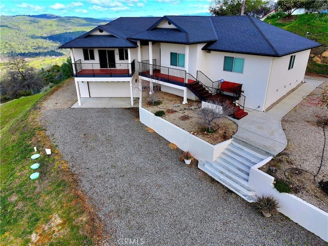 view of front facade featuring a garage, driveway, stairs, and stucco siding