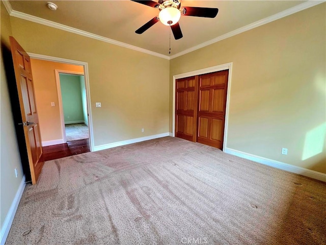 unfurnished bedroom featuring carpet, crown molding, a closet, a ceiling fan, and baseboards