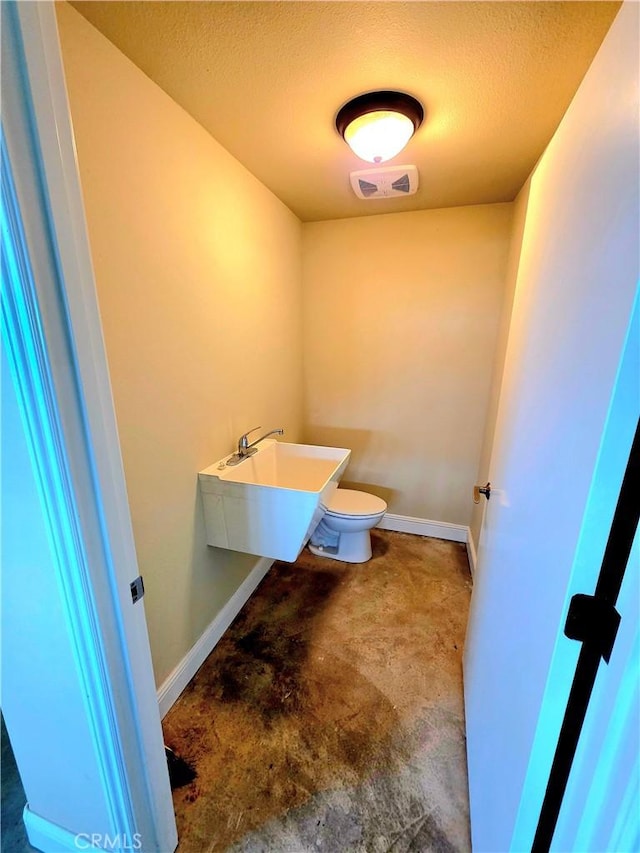 half bath featuring visible vents, unfinished concrete flooring, toilet, and baseboards