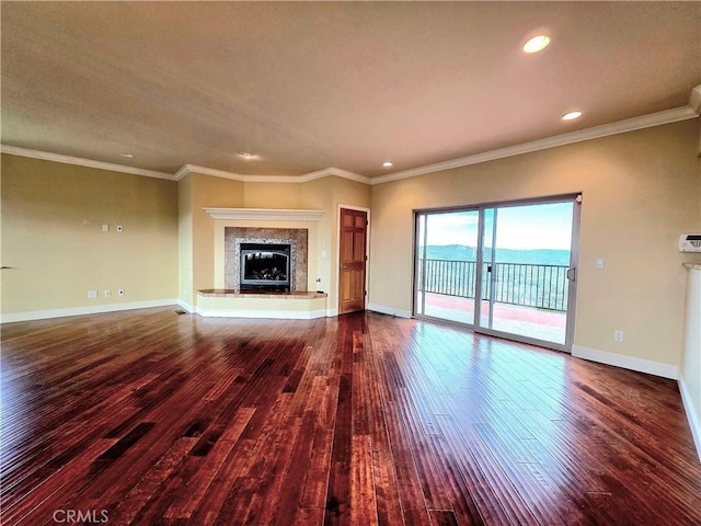 unfurnished living room with a premium fireplace, baseboards, wood finished floors, and ornamental molding