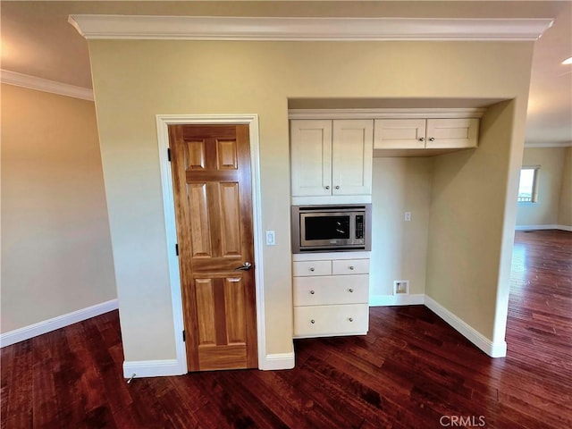 interior space with dark wood-type flooring, stainless steel microwave, and crown molding