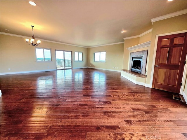 unfurnished living room featuring an inviting chandelier, a tiled fireplace, baseboards, and wood finished floors