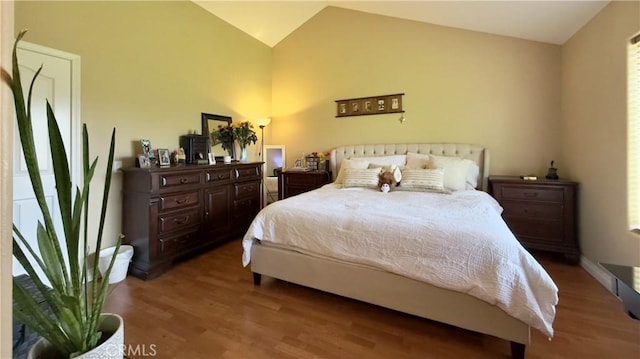 bedroom with vaulted ceiling, baseboards, and wood finished floors