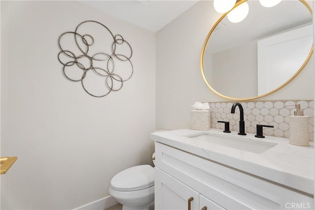 bathroom with toilet, backsplash, vanity, and baseboards