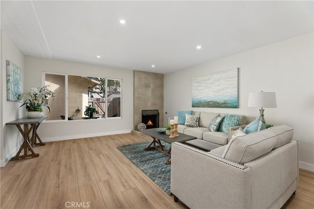 living area with a large fireplace, wood finished floors, and baseboards