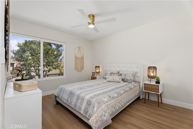 bedroom featuring a ceiling fan, baseboards, and wood finished floors