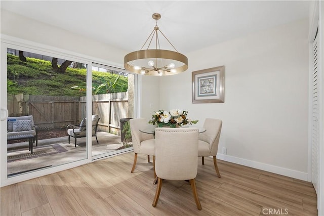 dining area featuring baseboards, wood finished floors, and a notable chandelier