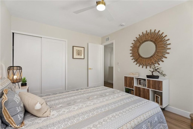 bedroom featuring wood finished floors, a ceiling fan, visible vents, baseboards, and a closet