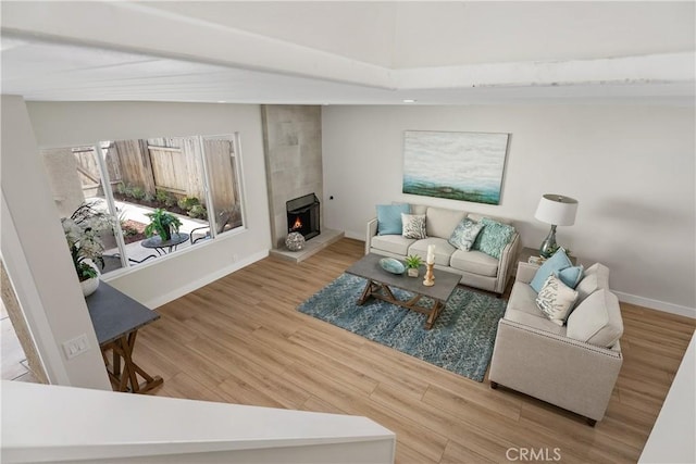 living area featuring a fireplace, baseboards, and wood finished floors