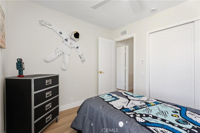 bedroom with a ceiling fan, light wood-style flooring, visible vents, and baseboards