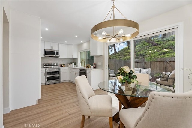 dining space with recessed lighting, a notable chandelier, and light wood-style flooring