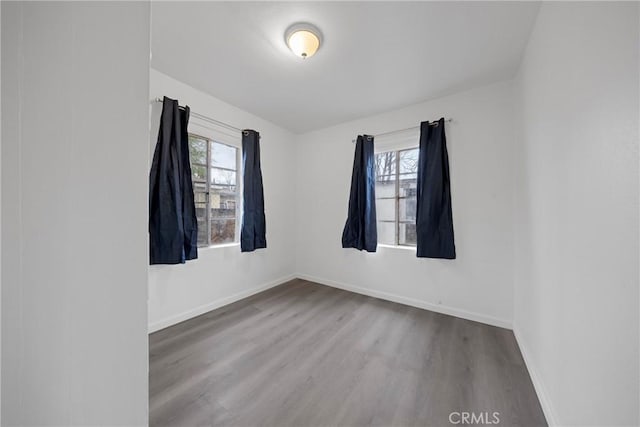 empty room with plenty of natural light, wood finished floors, and baseboards