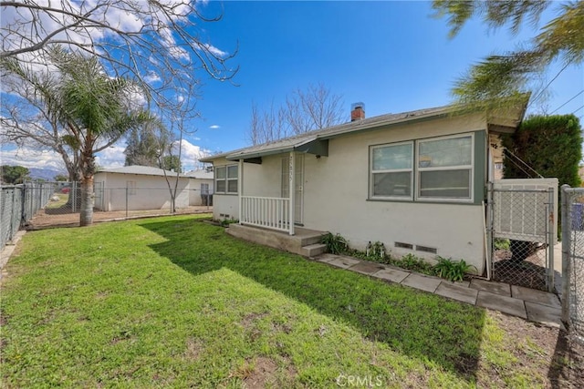 rear view of house with a yard, stucco siding, a gate, crawl space, and a fenced backyard