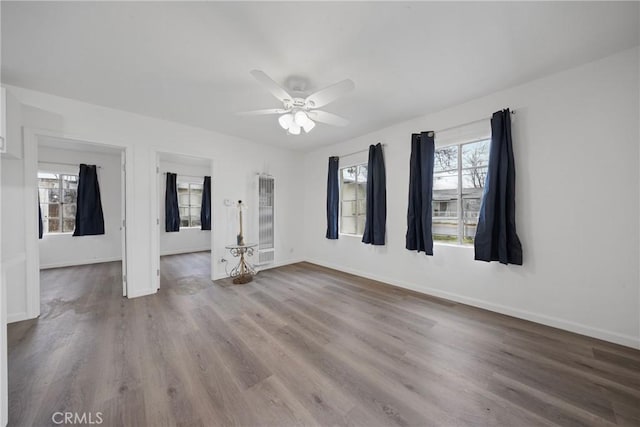 empty room with a ceiling fan, baseboards, and wood finished floors